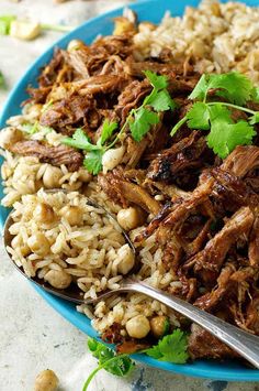 a blue plate topped with rice and meat next to garnished cilantro