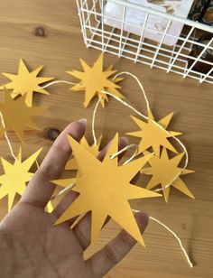 someone is holding some yellow paper stars in their hand on a wooden table with other items