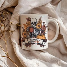 a coffee mug with a skeleton and sunflowers on it sitting on a bed