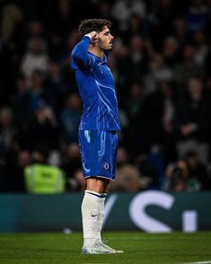 a soccer player is standing on the field with his head in his hands and looking up