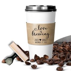 a coffee cup with the words love is brewing on it next to some nuts and a scoop