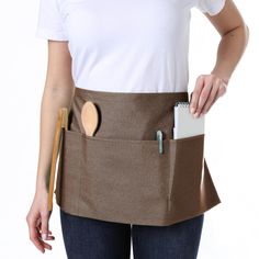 a woman wearing a brown apron with wooden spoons in her pocket