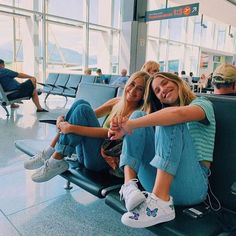 two people sitting in an airport waiting for their luggage