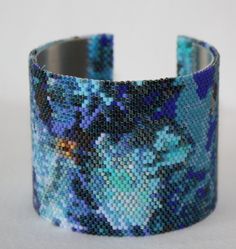 a close up of a bracelet on a white surface with blue and purple flowers in it