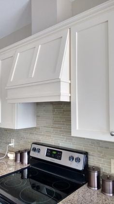 a stove top oven sitting inside of a kitchen next to white cabinets and counter tops