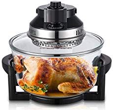 an oven with a roasting pan on the side and a chicken in it's center