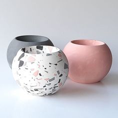 two vases sitting next to each other on a white surface with black and pink designs