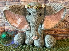 an elephant with a flower crown on its head sitting in front of a wooden wall