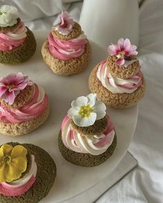 there are many cupcakes on the plate with pink icing and flowers in them