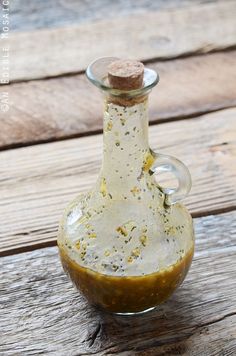 a glass bottle filled with mustard sitting on top of a wooden table covered in dirt