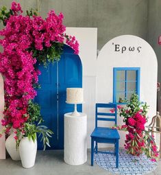 a blue chair sitting next to a white vase filled with pink flowers