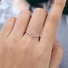 a woman's hand with a wedding ring on her finger, next to a green plant