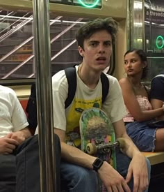 a group of people sitting on a subway car with skateboards in their hands and one person holding a skateboard