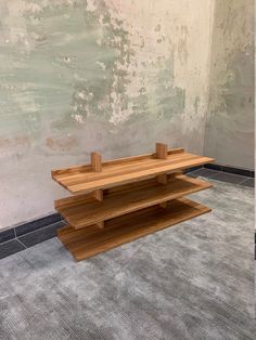 a wooden shelf sitting on top of a carpeted floor next to a white wall