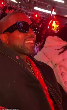 a man in sunglasses sitting next to a woman at a concert with other people behind him