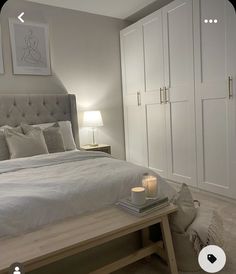 a bedroom with a large bed and white cupboards in the corner, next to a table with a lit candle on it