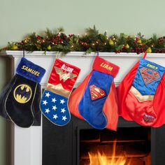 christmas stockings hanging from the fireplace in front of an image of batman and wonder symbols