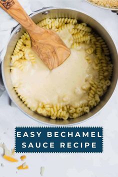 a pot filled with pasta and sauce on top of a counter next to a wooden spoon