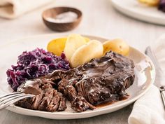 a white plate topped with meat, potatoes and cabbage