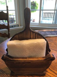 a wooden holder with two rolls of toilet paper in it on top of a table