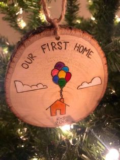 a wooden ornament hanging on a christmas tree with the words, our first home