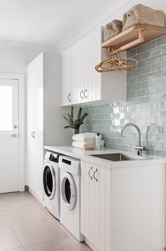 a washer and dryer in a white laundry room with blue tiled backsplash