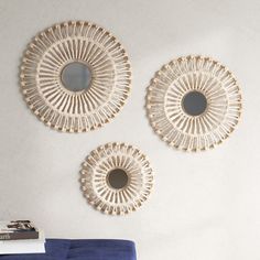 three circular mirrors mounted on the wall above a blue couch in front of a white wall