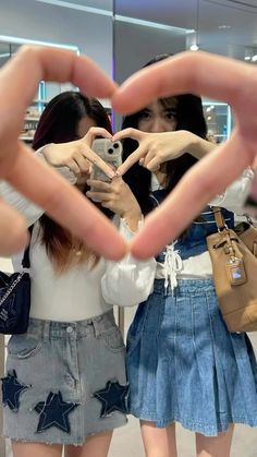 two girls making heart shape with their hands