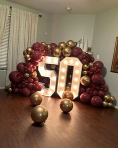 a 50th birthday decoration with balloons and lights on the table in front of a large sign that reads 50