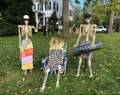 three skeletons sitting on lawn chairs in front of a house