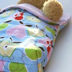 a stuffed animal laying on top of a blue and pink blanket with an apple print