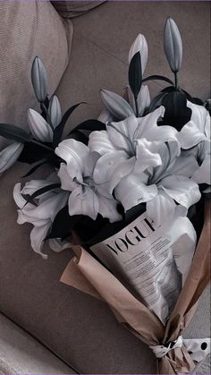 a bouquet of flowers sitting on top of a couch next to a bag with an article in it