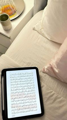 a tablet sitting on top of a bed next to pillows