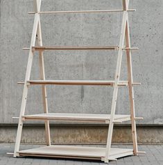 a white wooden shelf sitting on top of a brick floor next to a cement wall