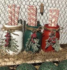 three mason jars with candy canes in them are sitting on a shelf next to other christmas decorations