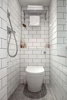 a white toilet sitting inside of a bathroom next to a walk in shower and tiled walls