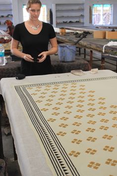 a woman standing next to a table covered in fabric