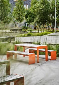 an empty park with benches and trees in the background