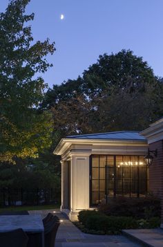 an outdoor patio at night with the moon in the sky above it and lights on