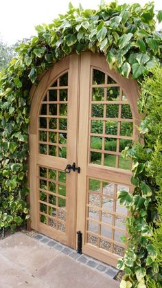 an arched wooden door surrounded by greenery