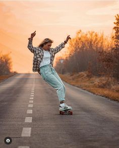 a woman riding a skateboard down the middle of a road