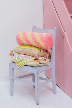 a chair with blankets on it next to a stair case and pink painted wall in the background