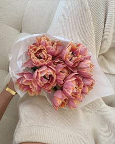 a bouquet of pink flowers sitting on top of a white couch next to a person's arm