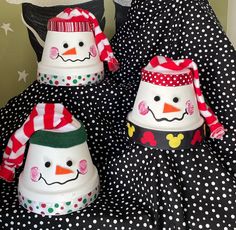 three snowmen wearing hats and scarves on top of a black polka dot dress