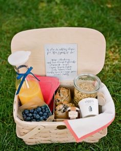 a picnic basket filled with food and drinks on top of a grass covered park area