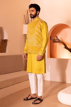 Yellow sleeveless waistcoat with all over hand embroidery in threads, sequins, beads and cutdana
Components: 1
Pattern: Hand Embroidery
Type Of Work: Beads, Sequins, Thread
Neckline: Round Neck
Sleeve Type: Sleevekess
Fabric: Padma Silk
Color: Yellow
Other Details: 
Note:
Kurta and pant worn by the model is not for sale
The outfits worn by the models at the back is not for sale
Occasion: Sangeet - Aza Fashions Geometrical Embroidery, Yellow Waistcoat, Hand Embroidery Beads, Kurta And Pants, Sleeveless Waistcoat, Embroidery Beads, Waistcoat Men, Indian Wedding Wear, Nehru Jackets