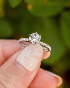 a close up of a person's hand holding a ring with a diamond on it