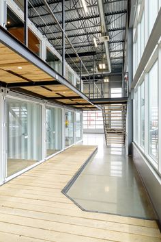 the inside of an industrial building with wooden floors and glass doors on either side of the walkway