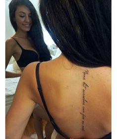 a woman with a tattoo on her back is looking at another woman in the mirror