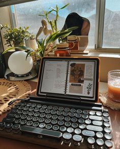 an open laptop computer sitting on top of a wooden desk next to a plant and potted plants